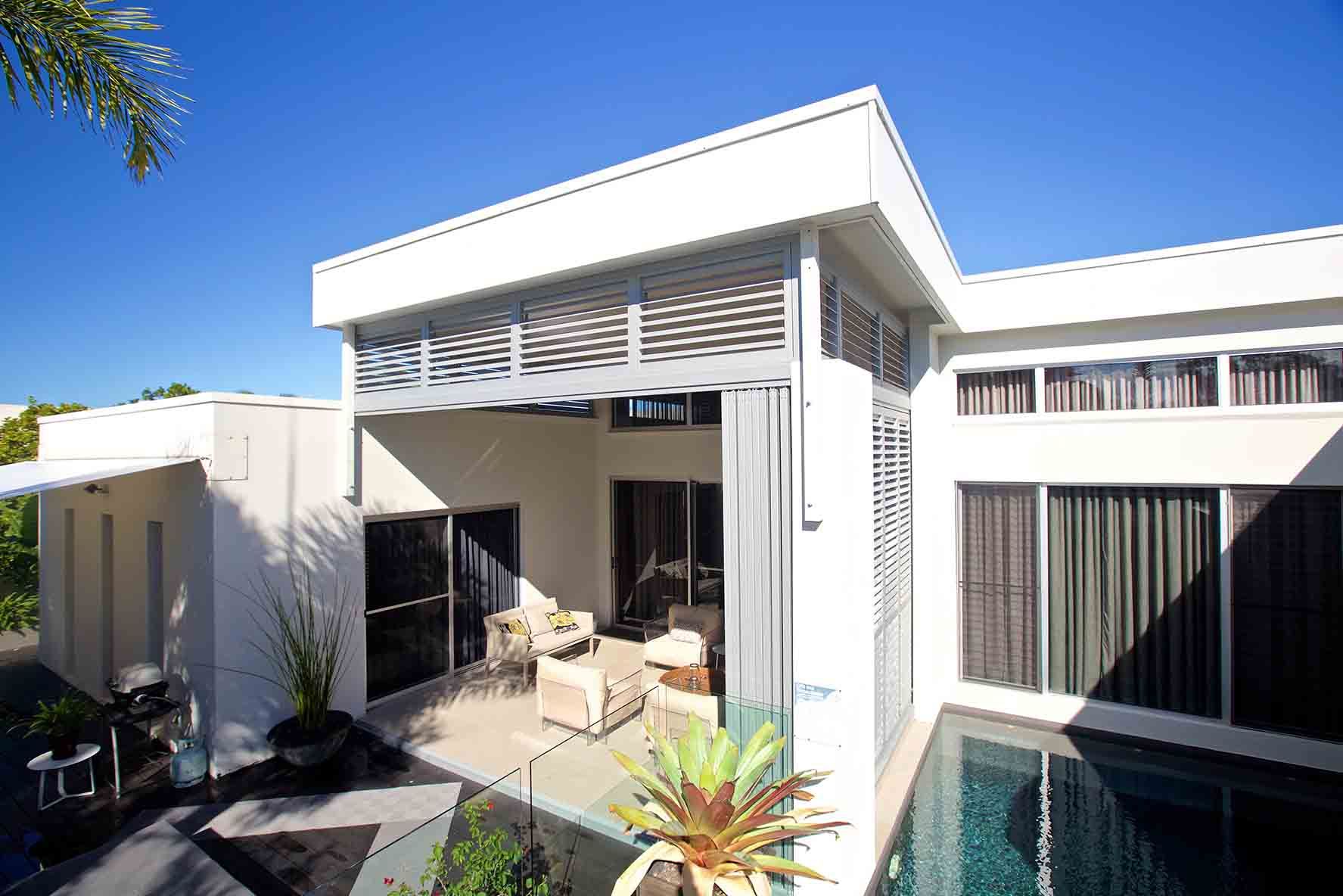 A White House With A Swimming Pool In Front Of It — Balcony Shutters Australia In Moffat Beach, QLD