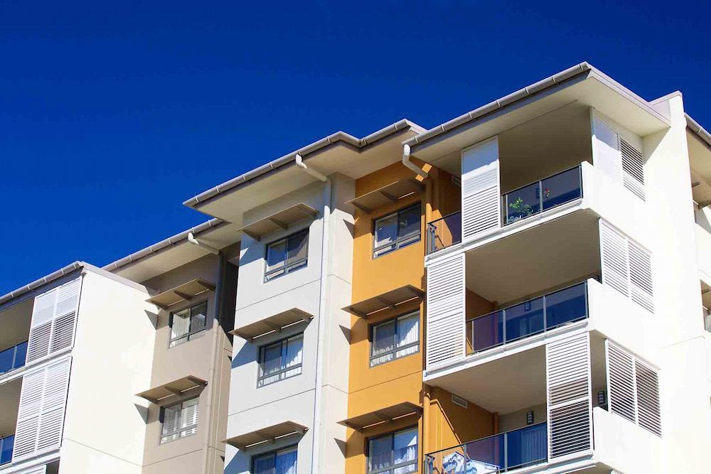 A Large Apartment Building With A Blue Sky In The Background — Balcony Shutters Australia In Moffat Beach, QLD