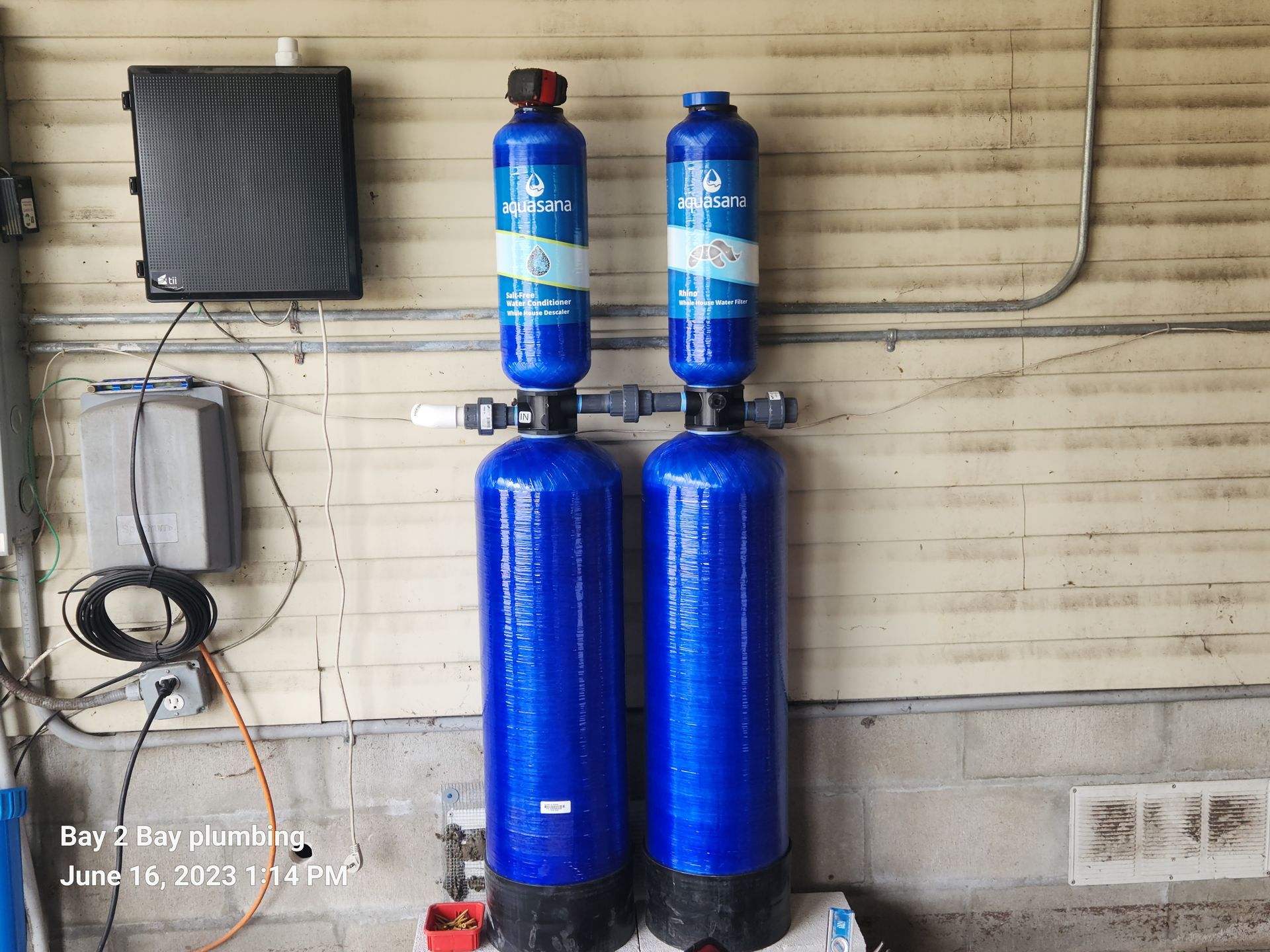 Two blue gas cylinders mounted outside beside a wall and utility box