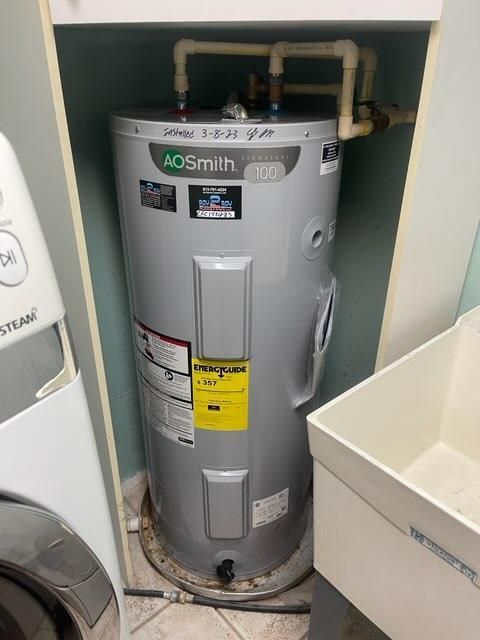 A.O. Smith water heater in a small utility closet with pipes and labels visible