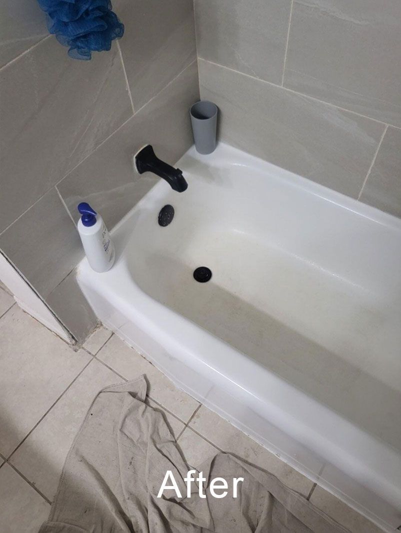 After photo of a bathtub with a black faucet, white bottle, and gray cup on beige tile bathroom floor