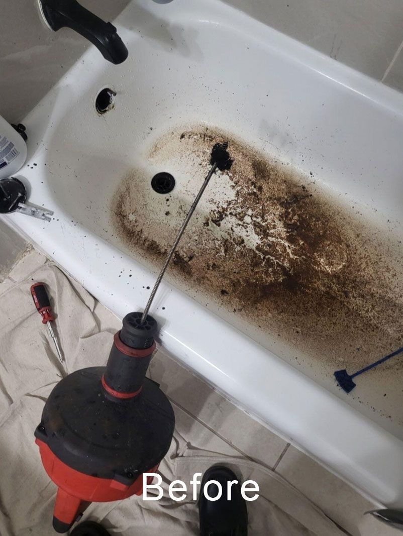 Dirty bathtub with brown grime, being scrubbed with a drill brush attachment.