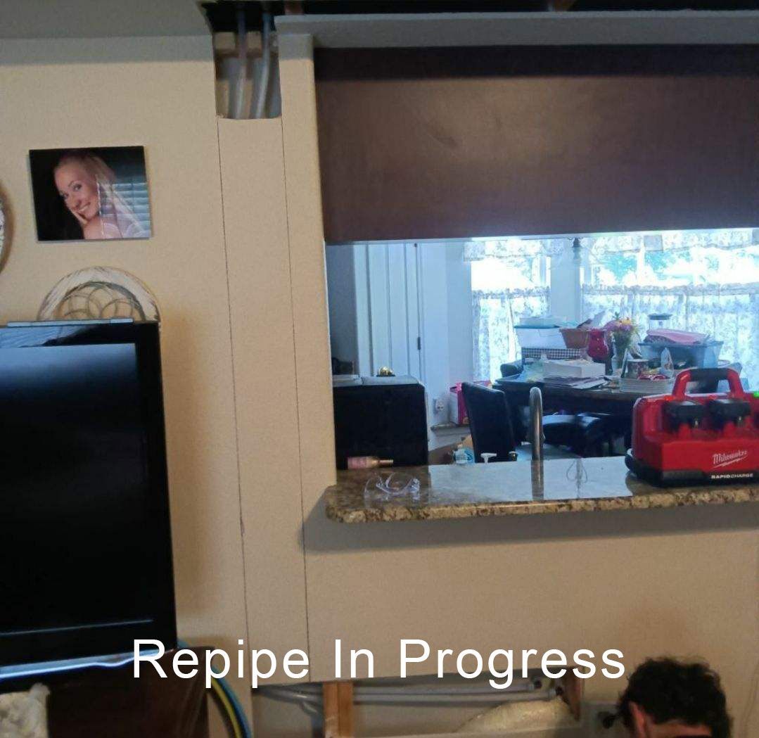 Indoor room with a wall cutout view, furniture in the background, and text reading “Repipe In Progress.”