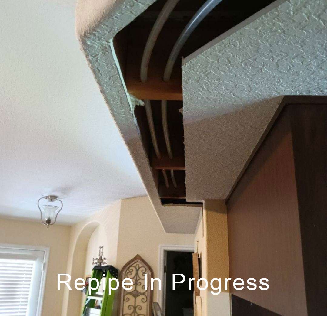Ceiling cutaway showing exposed pipes and ductwork during home repair in a hallway