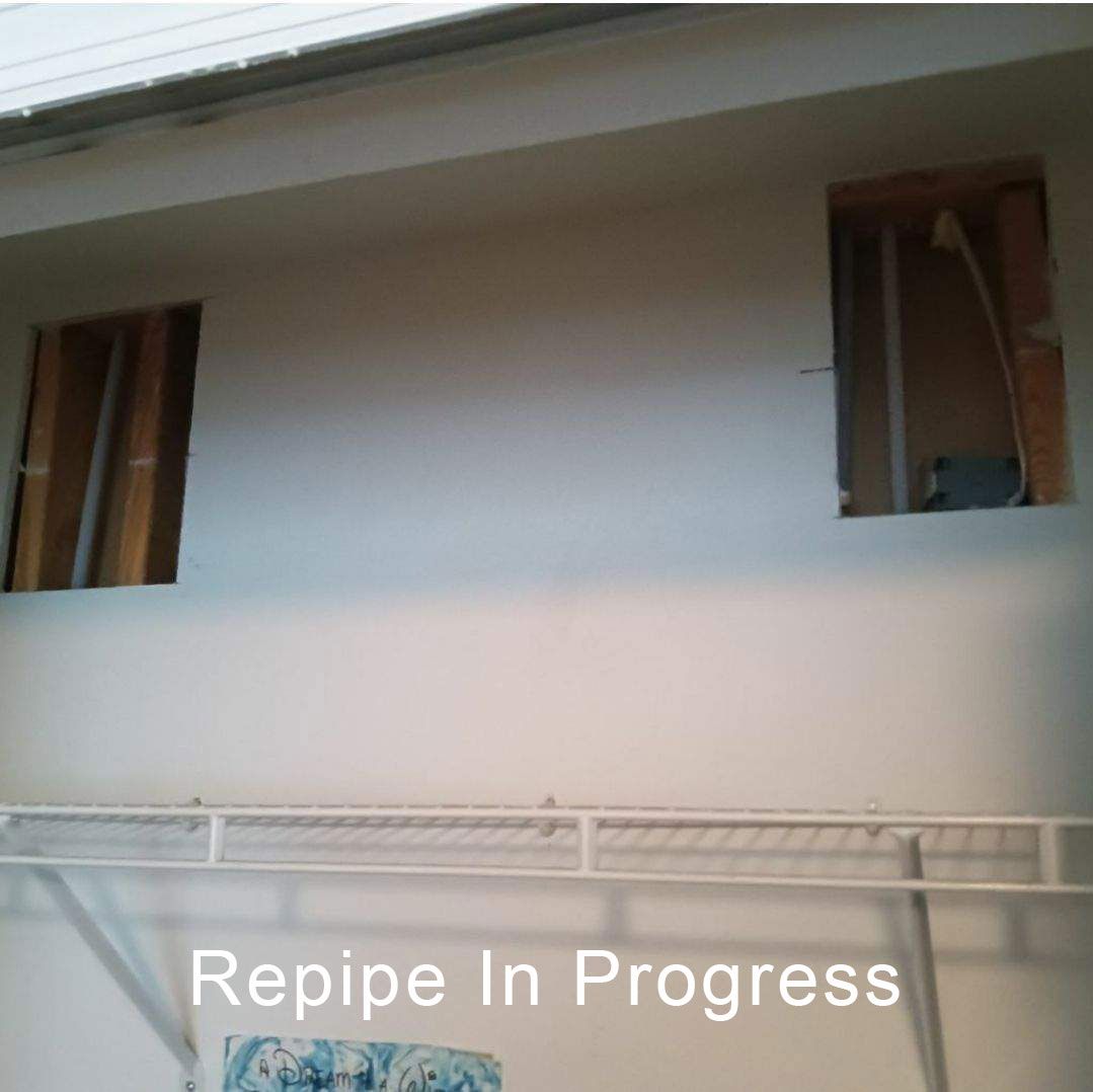 White exterior wall with open window gaps and scaffolding below, labeled “Repipe In Progress”