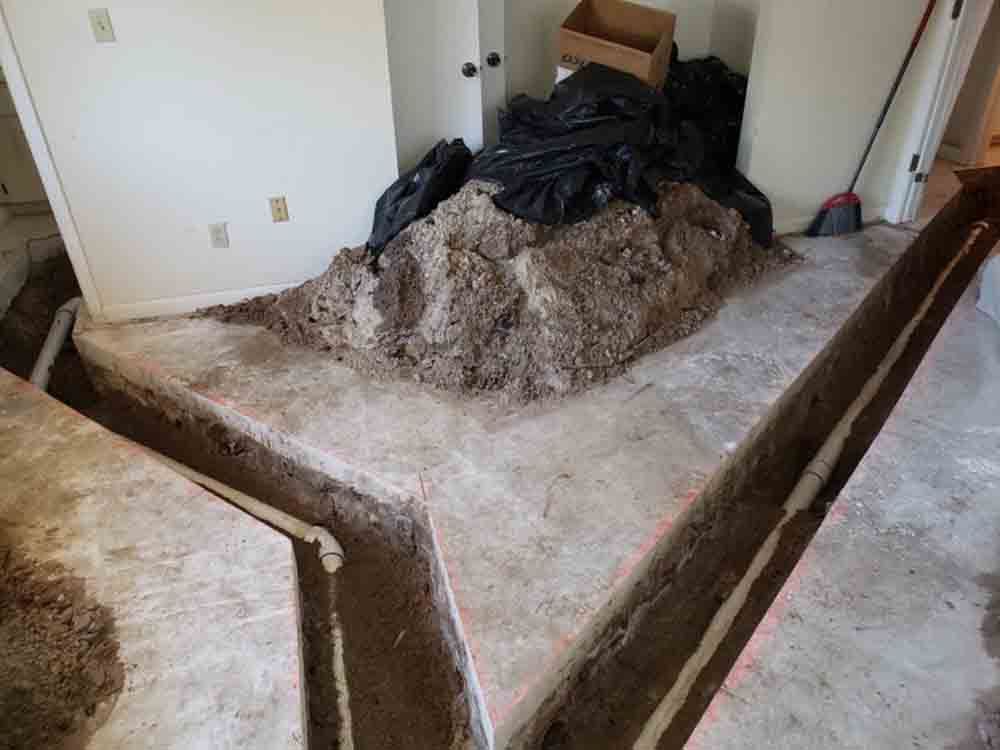 Room with severe water damage and mold-stained carpet, showing a large pile of debris near a wall.