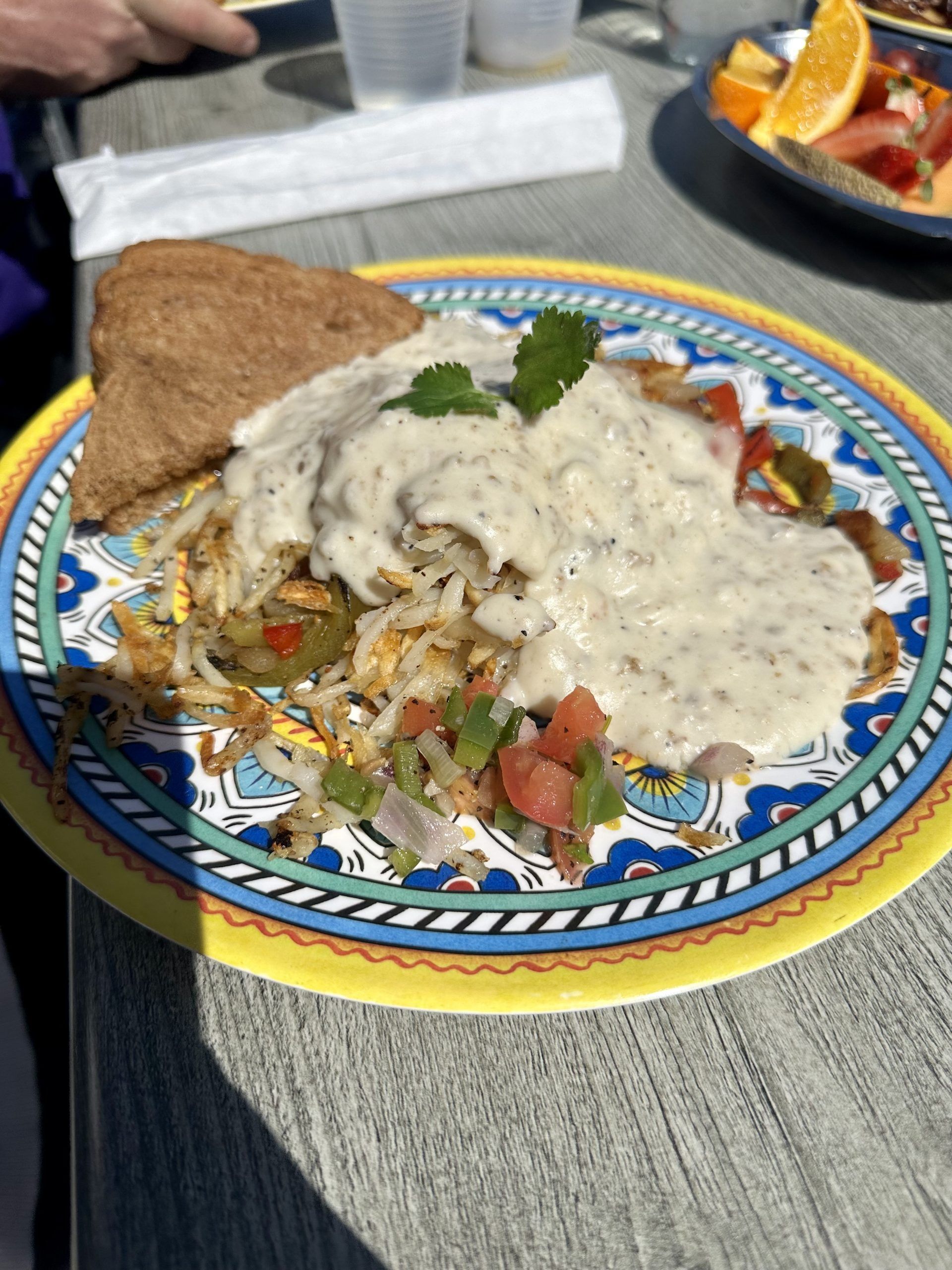 Plate of food with creamy sauce, rice and vegetables, plus a piece of flatbread on a colorful patterned dish.