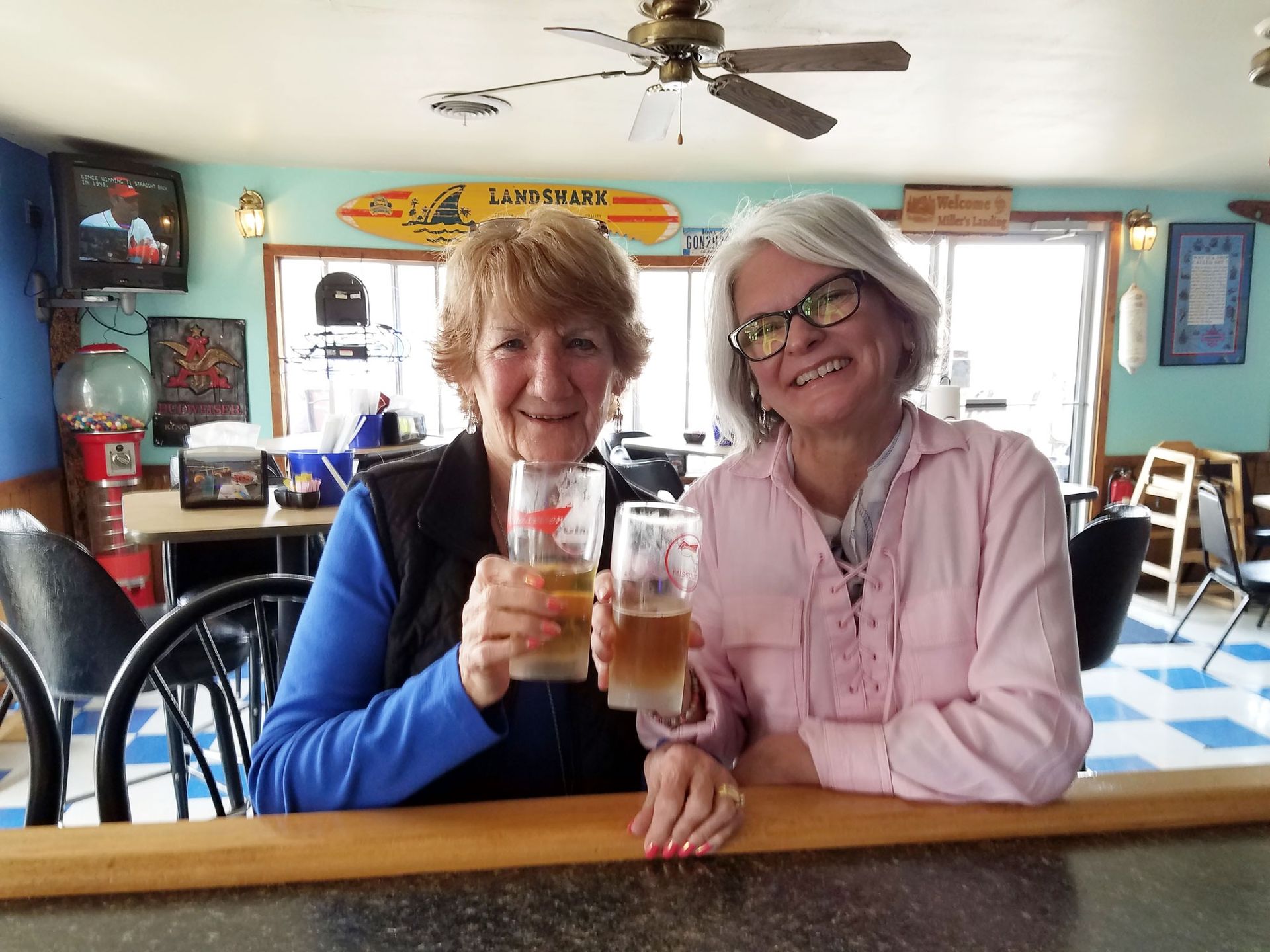Two women smiling and holding drinks at a bar in a casual café setting