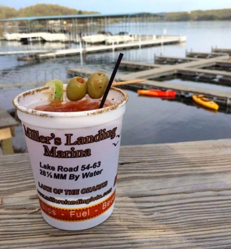 Cocktail with olives on a dock rail overlooking a marina and calm lake