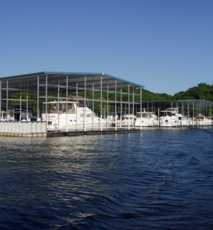 Covered marina with white boats docked on calm blue water under a clear sky