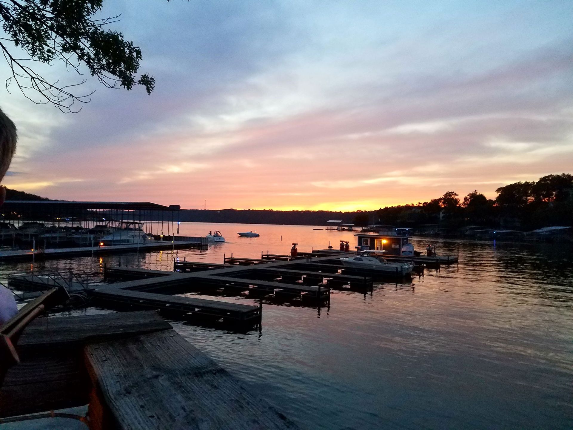 Sunset over a calm harbor with moored boats and glowing reflections on the water