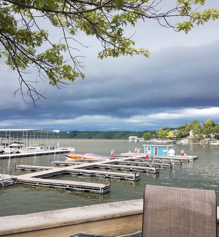 Marina with docked boats under dark storm clouds, viewed from a lakeside deck.