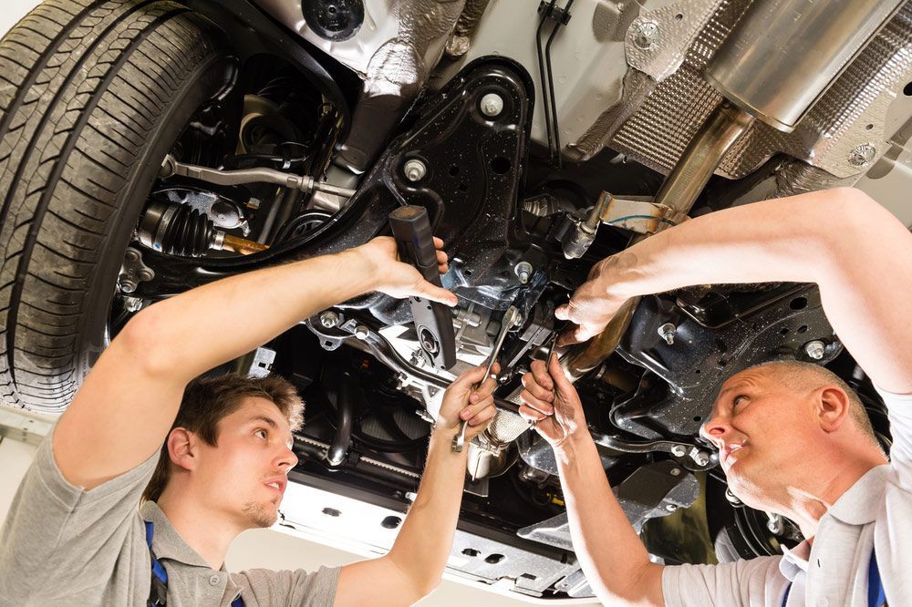 Two Auto Mechanics Working Underneath A Lifted Car — Torque Masters Auto Repairs Centre In Portsmith QLD