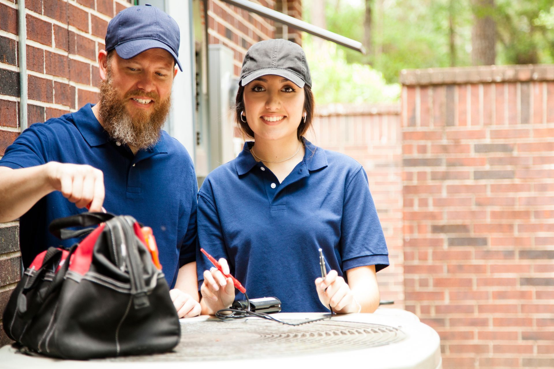 Man and one woman repairing a home's air conditioner unit - Tallahassee, FL - Todd King's Heating and Cooling Man and one woman repairing a home's air conditioner unit - Tallahassee, FL - Todd King's Heating and Cooling
