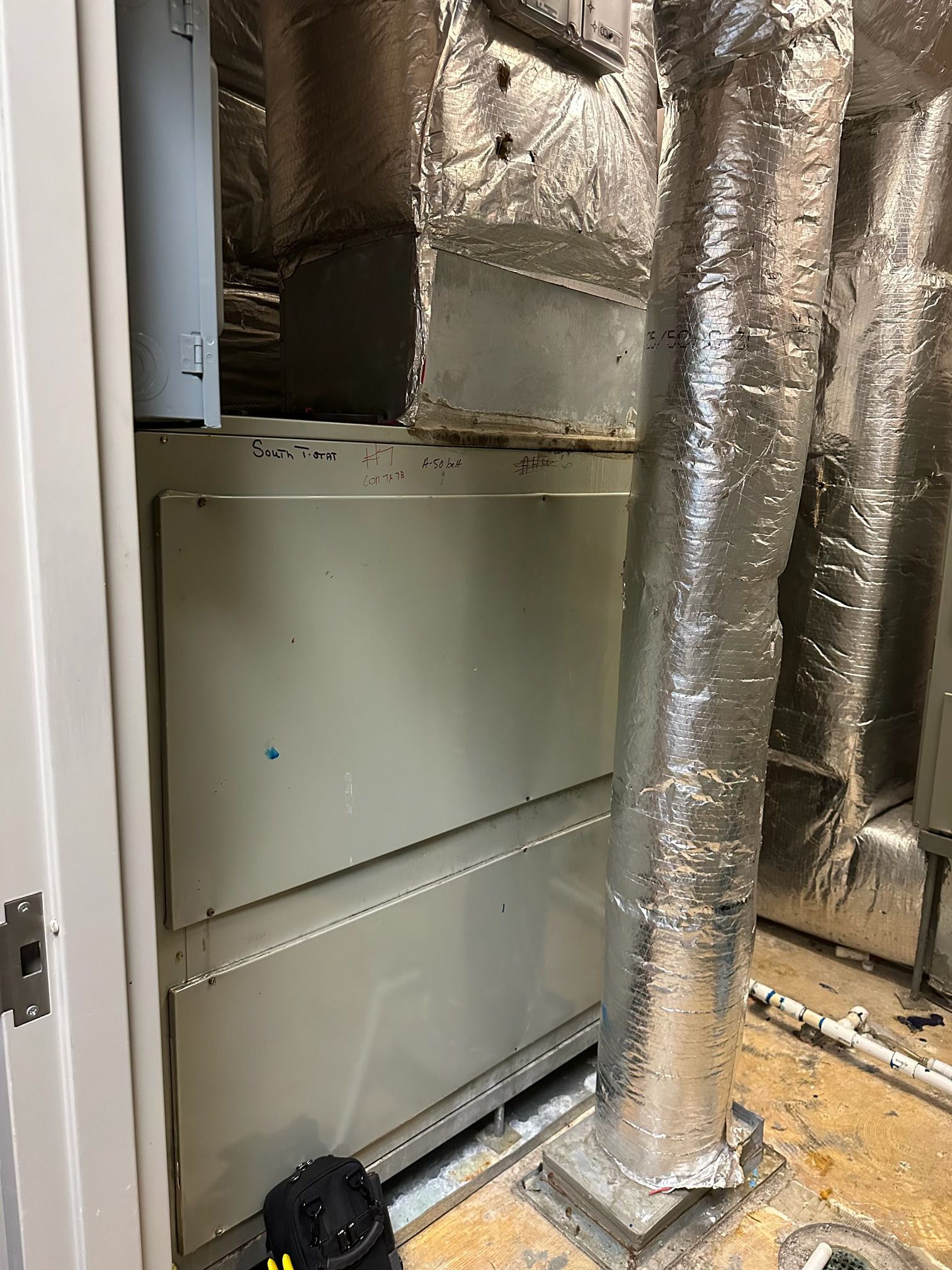 An HVAC air handler unit with insulated ductwork in a closet, viewed from a slightly high angle.