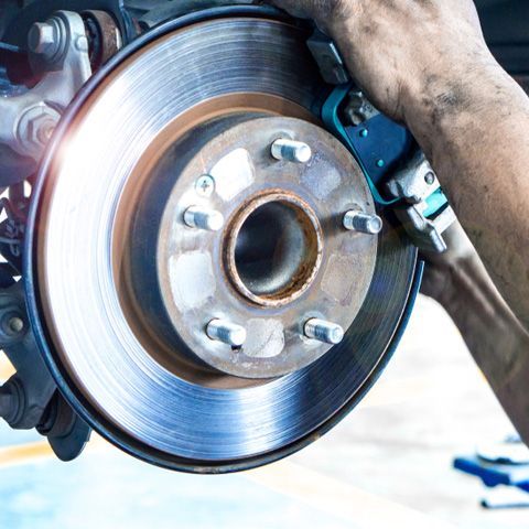 A Person Is Fixing A Brake Disc On A Car — APPS Mechanical Port Macquarie In Port Macquarie, NSW
