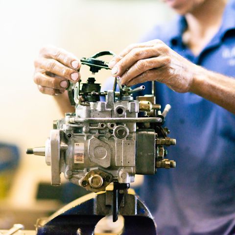 A Man In A Blue Shirt Is Working On A Fuel Pump — APPS Mechanical Port Macquarie In Port Macquarie, NSW