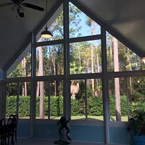 Large windows in a room overlook trees. A sculpture is in front of the windows.