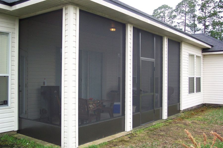 Screened-in porch on a house with dark screens, white trim, and a dark brown base.