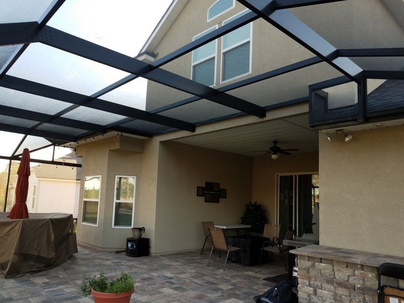 Patio with a screened aluminum cover, beige house, outdoor furniture.