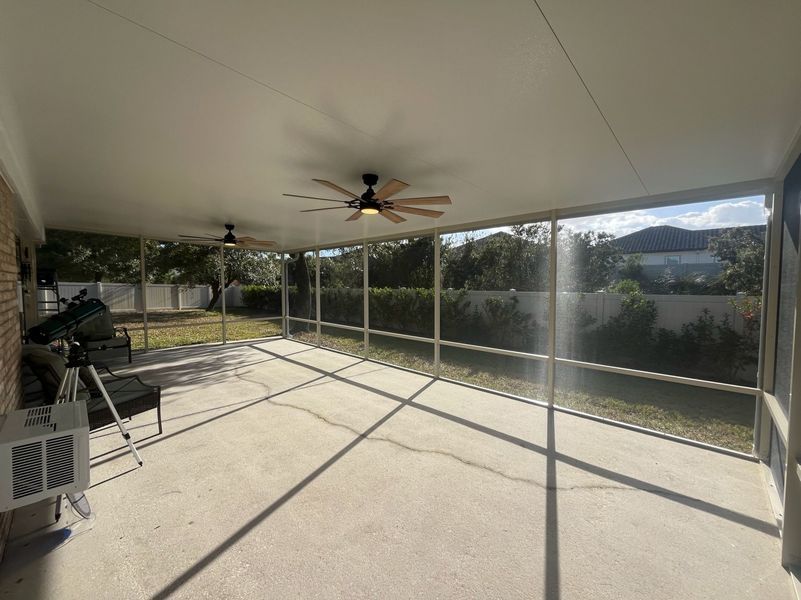 Covered outdoor patio with fans, screens, and concrete floor.