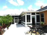 Modern backyard patio featuring a screen enclosure walkway connected to a bright glass enclosure sun