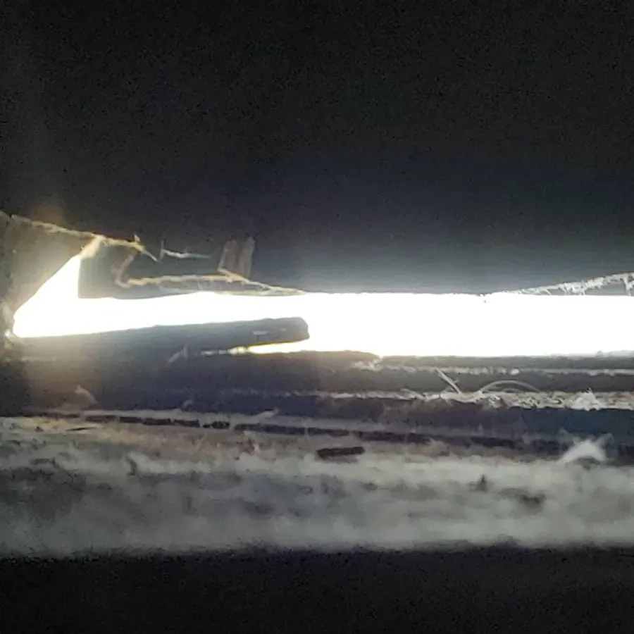 Dark gap under a door with bright daylight shining through a narrow opening