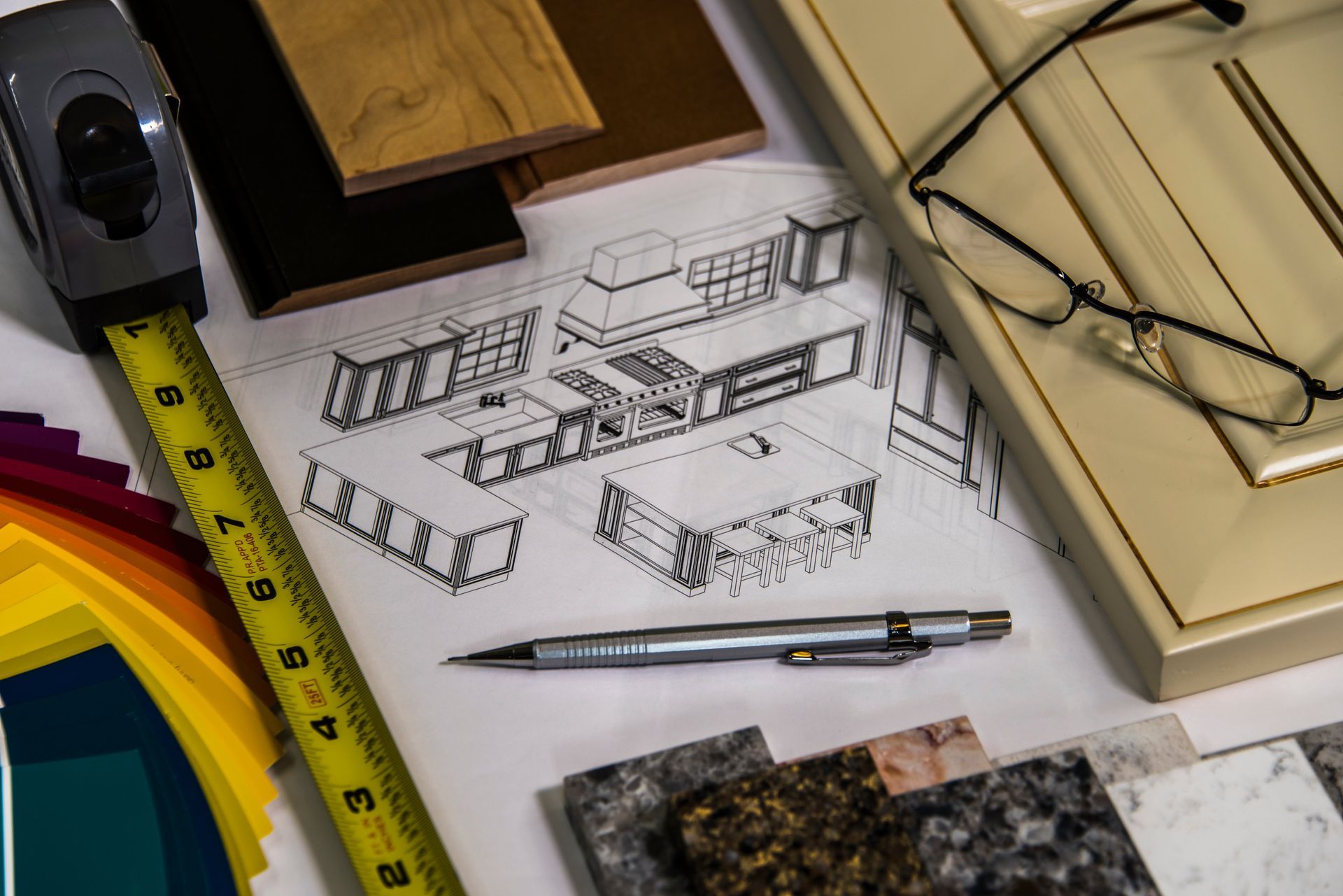 Kitchen design blueprint surrounded by cabinet samples, countertop swatches and tape measure.