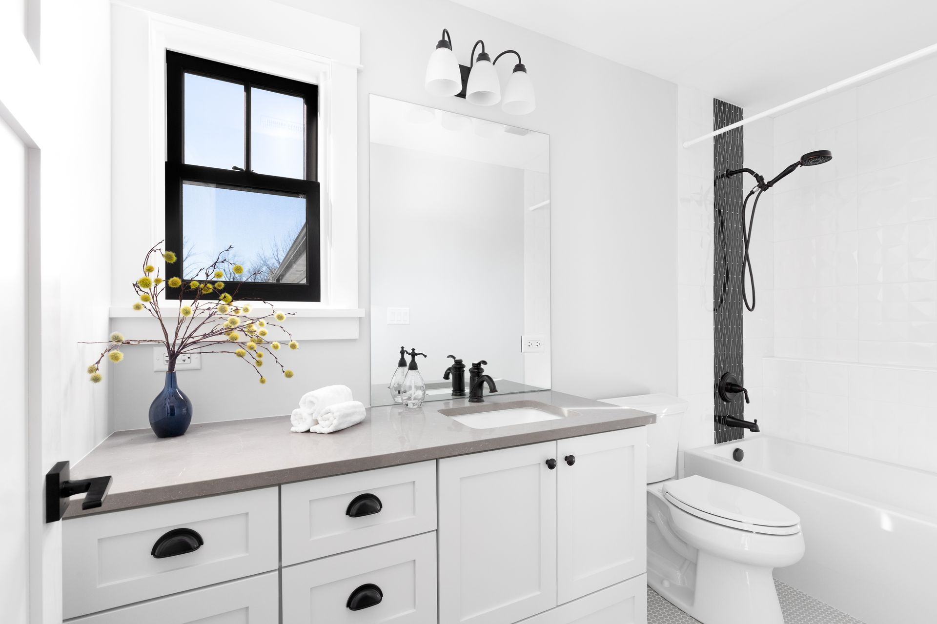 A luxury renovated white bathroom with a brown granite countertop.