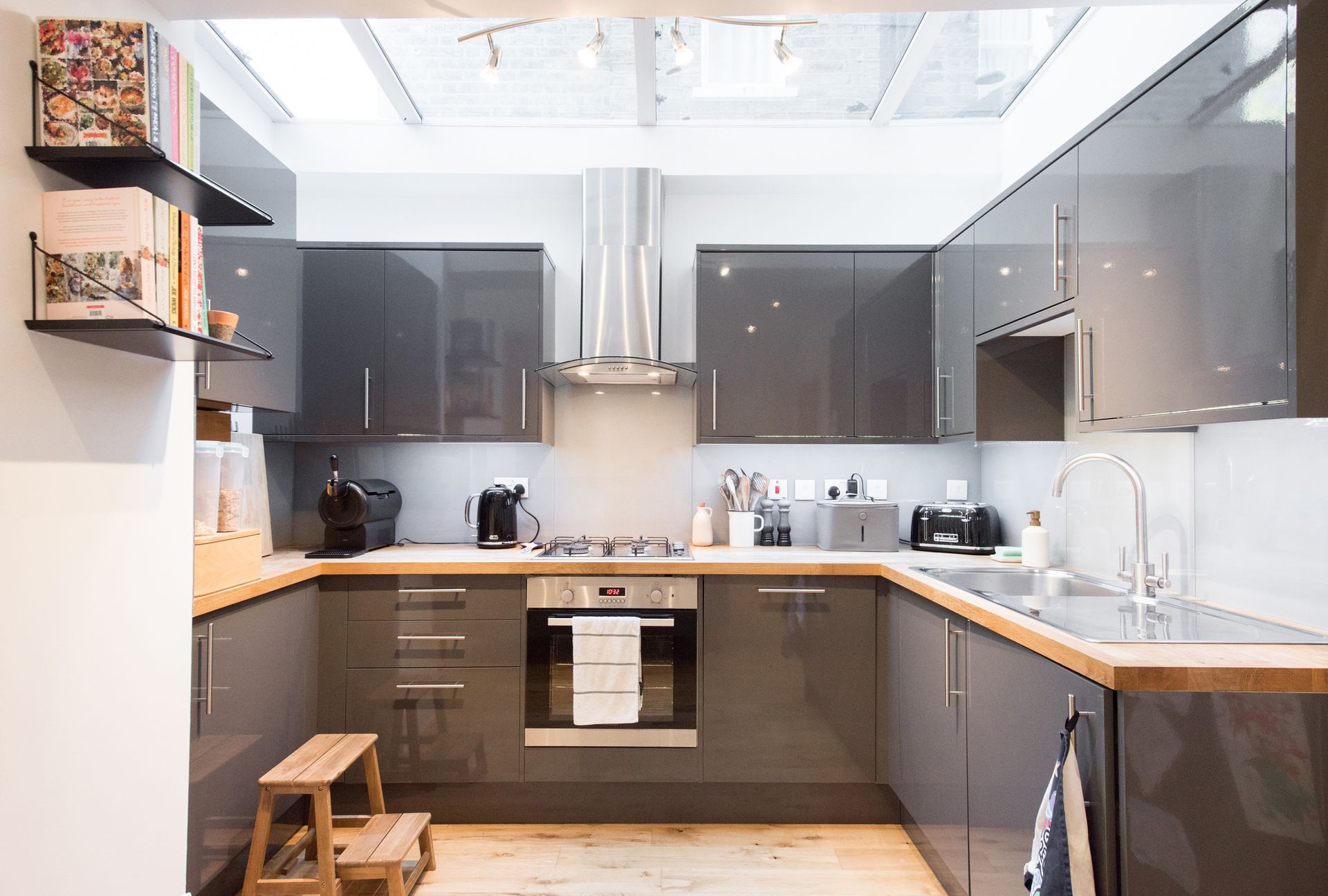 Modern kitchen with gray cabinets, wooden countertops, and stainless steel appliances.
