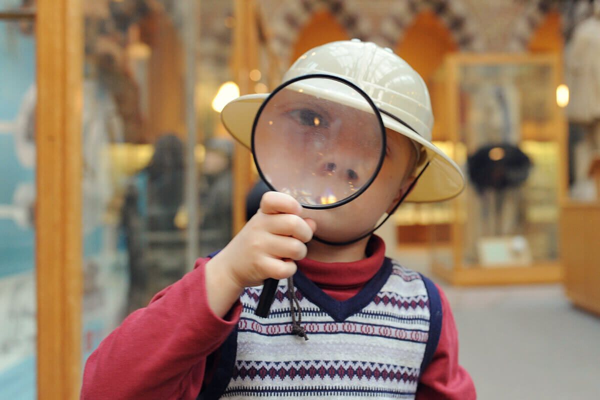 Child with magnifying glass in glass shop
