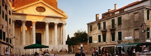 Campo San Nicola da Tolentino in Venice at sunset, featuring the church facade and local shops.