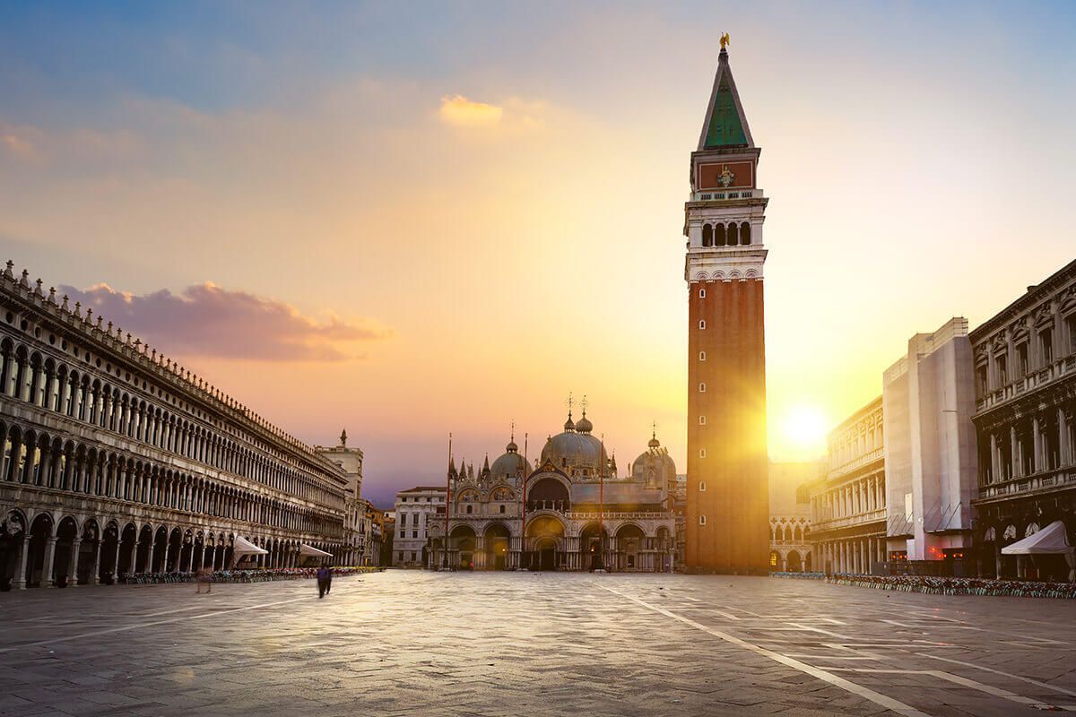 St. Mark's Square and the Bell Tower at sunset, with the warm golden light reflecting off the historic pavement and facades