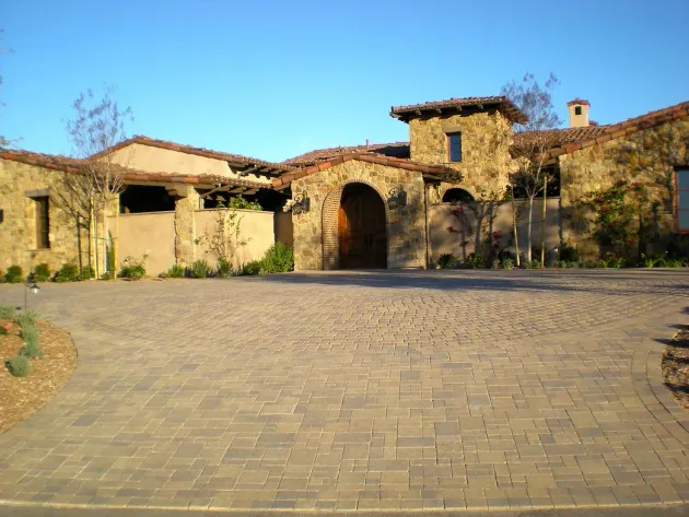 Claddagh Paving Corporation - a large stone house with a brick driveway in front of it