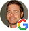 Smiling young man with light hair wearing a gray hoodie, Google logo in the corner.