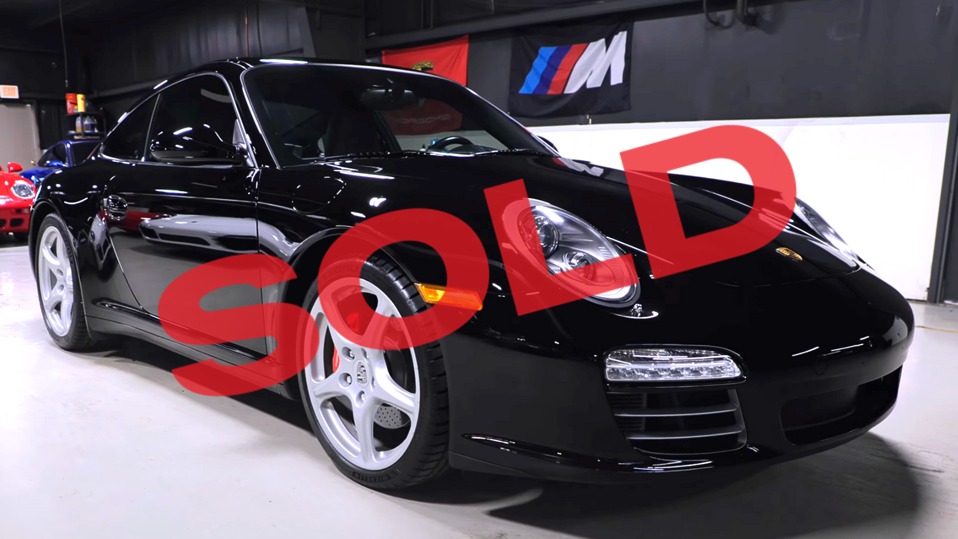 Black sports car in an indoor showroom with a large red 