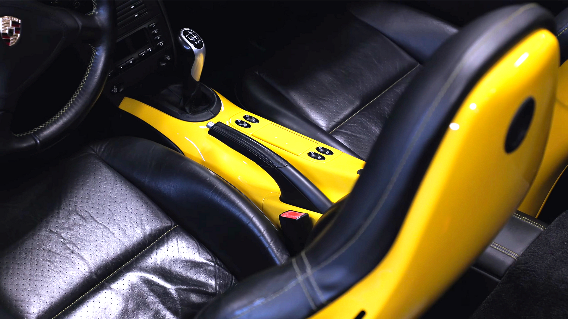 Yellow mobility aid resting on a black leather car seat next to a steering wheel.