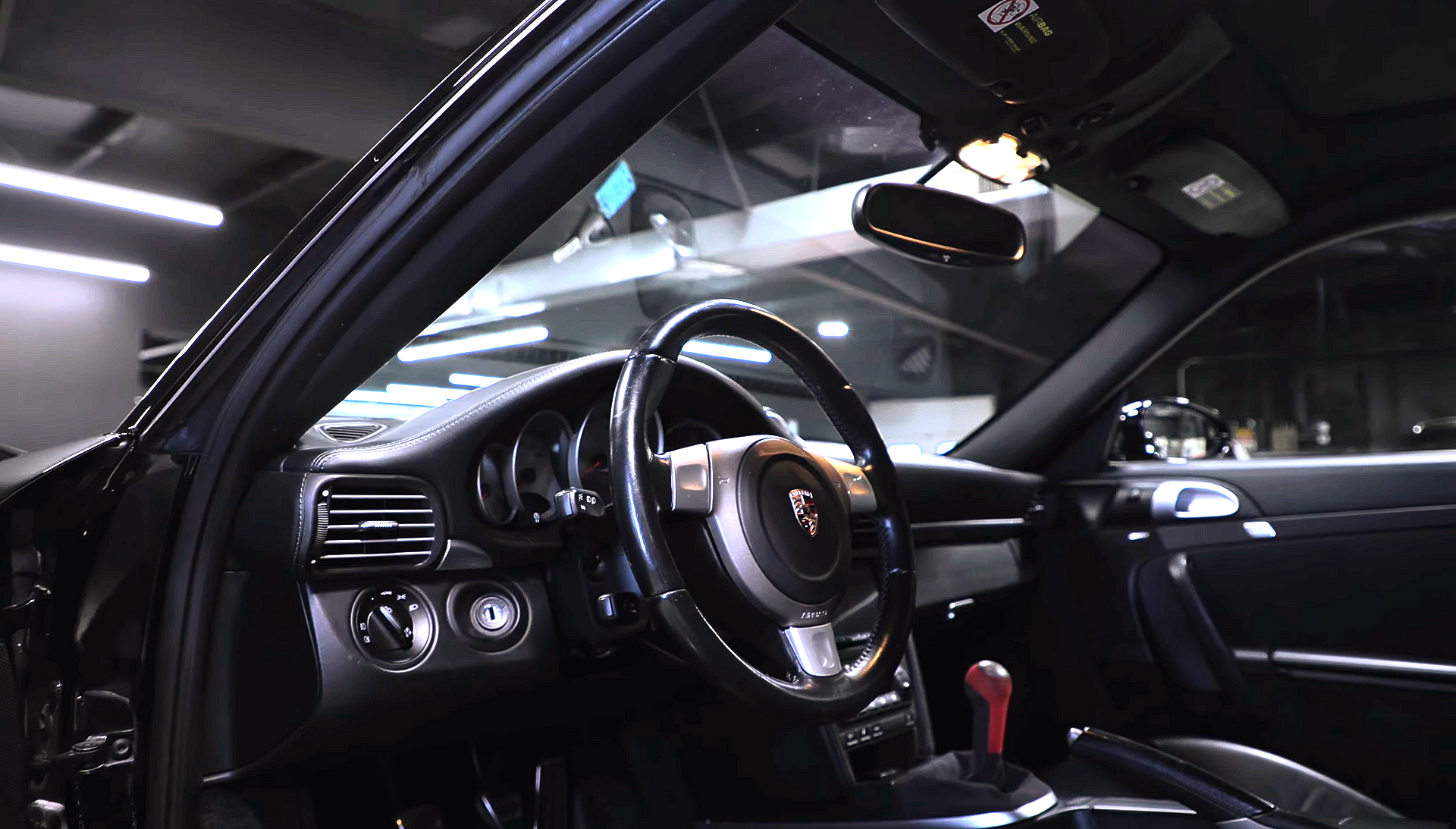 Luxury car interior with black leather seats, dashboard, steering wheel, and open driver door.