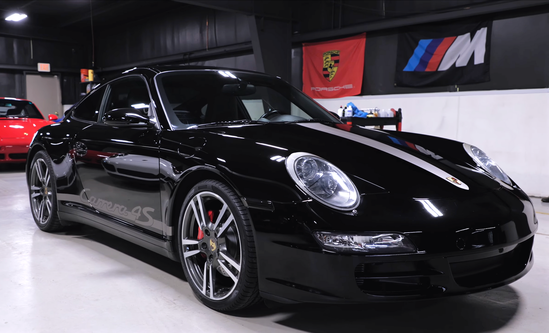 Black sports car in an indoor showroom with a large red 