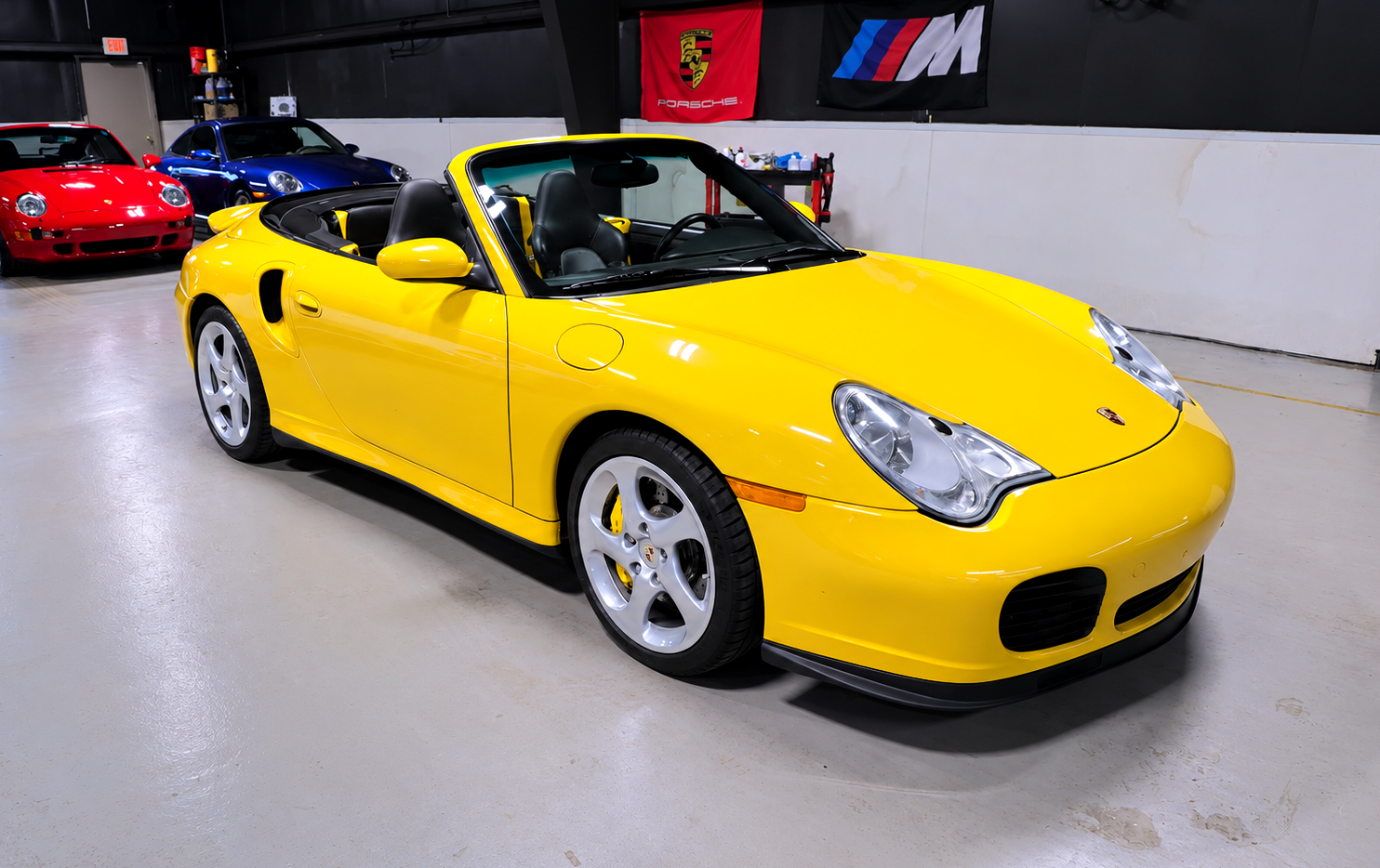 Black sports car in an indoor showroom with a large red 