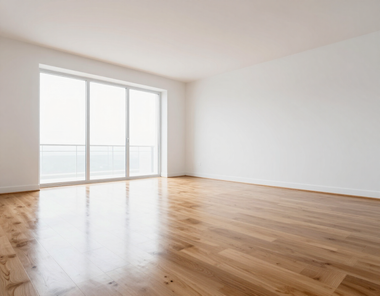 Empty bright room with hardwood floors and large sliding glass doors opening to a balcony.