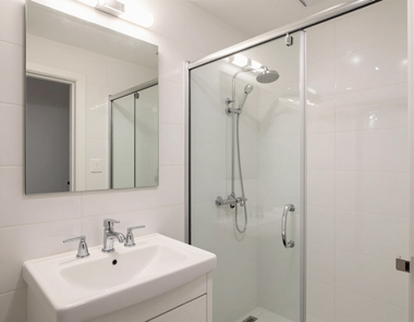 Modern white bathroom with sink, mirror, and glass shower enclosure