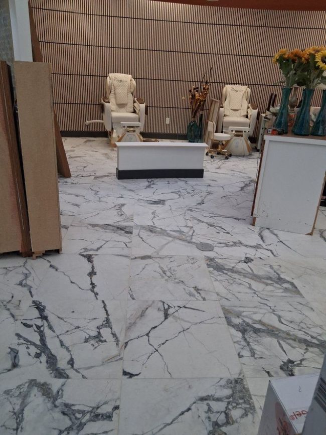 Indoor seating area with two beige chairs, a white table, and marble-patterned flooring.