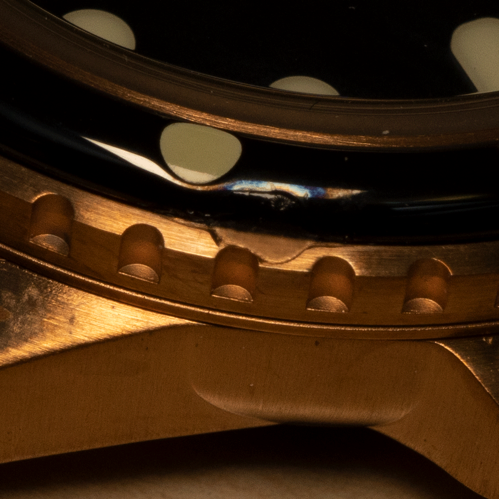 A close up of a gold watch with a black face