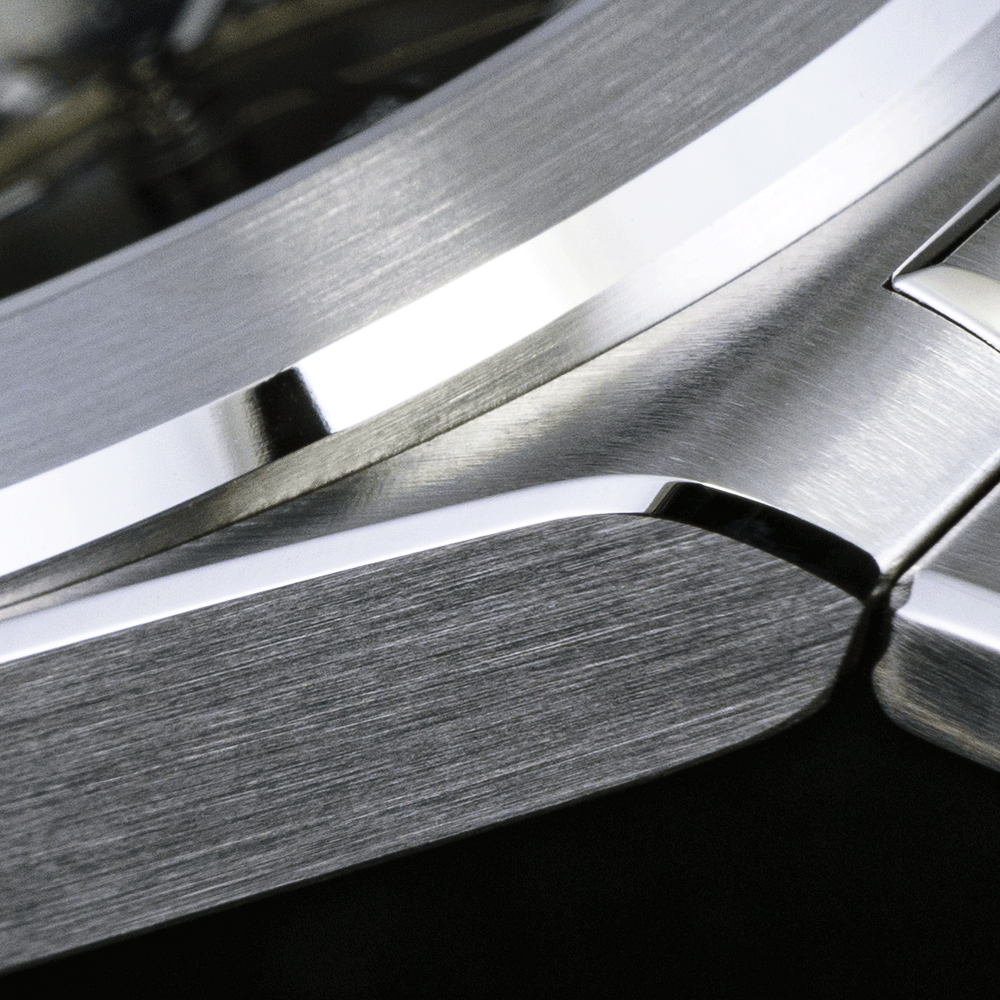 A close-up of a brushed stainless steel watch case and lug, highlighting the contrast between brushed and polished finish.