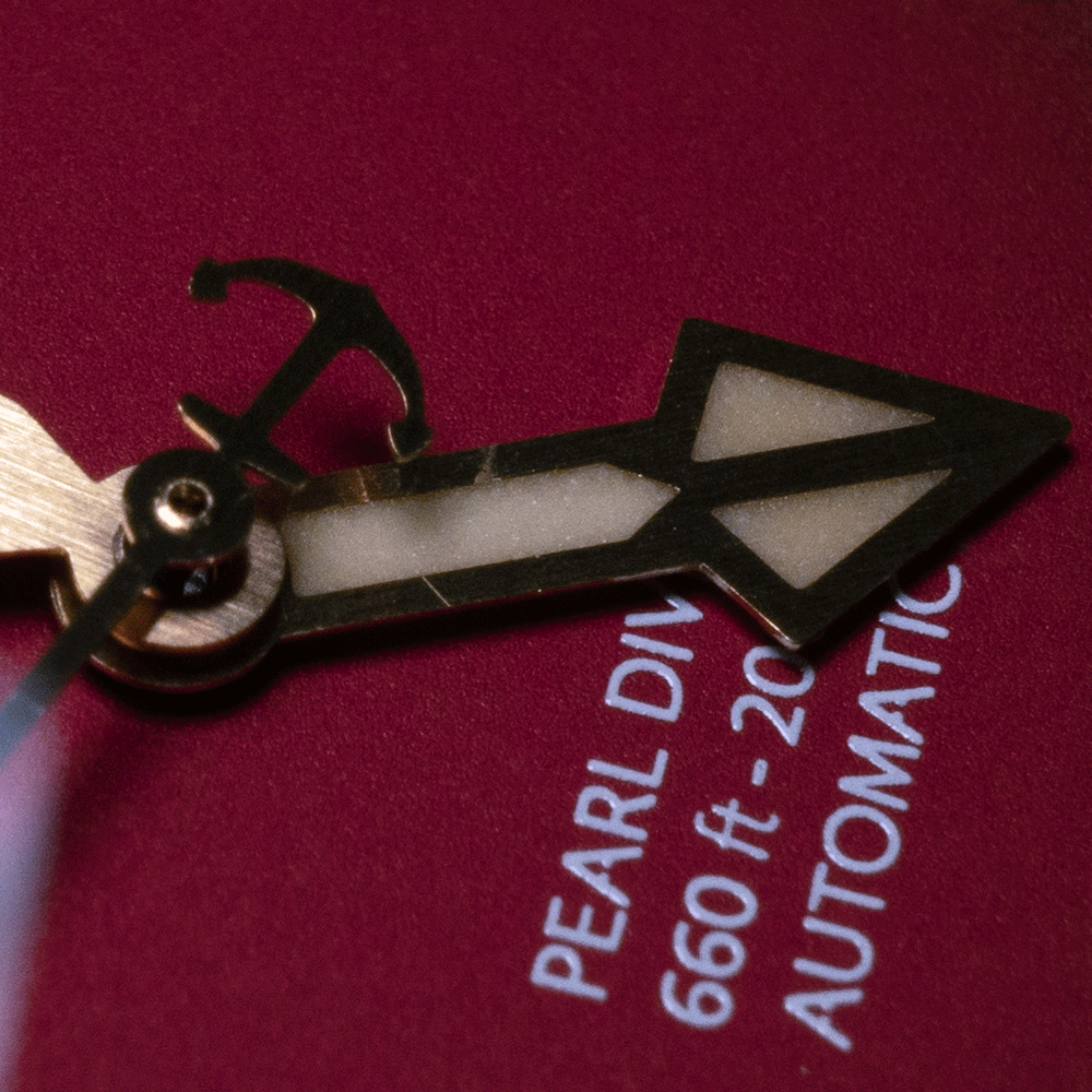 A close up of a pearl div 660 ft automatic watch face