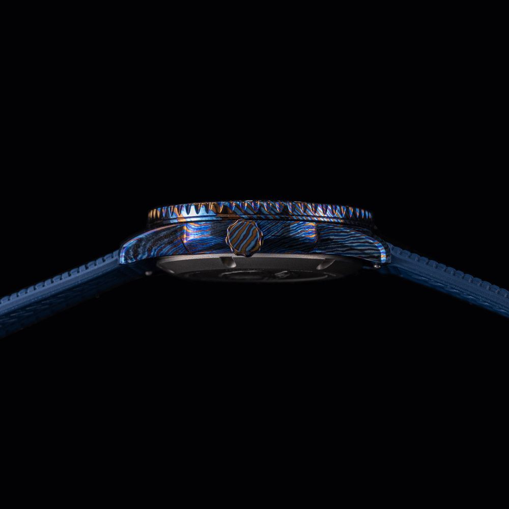 A side-view of a blue, patterned watch case with a matching blue textured strap against a black background.