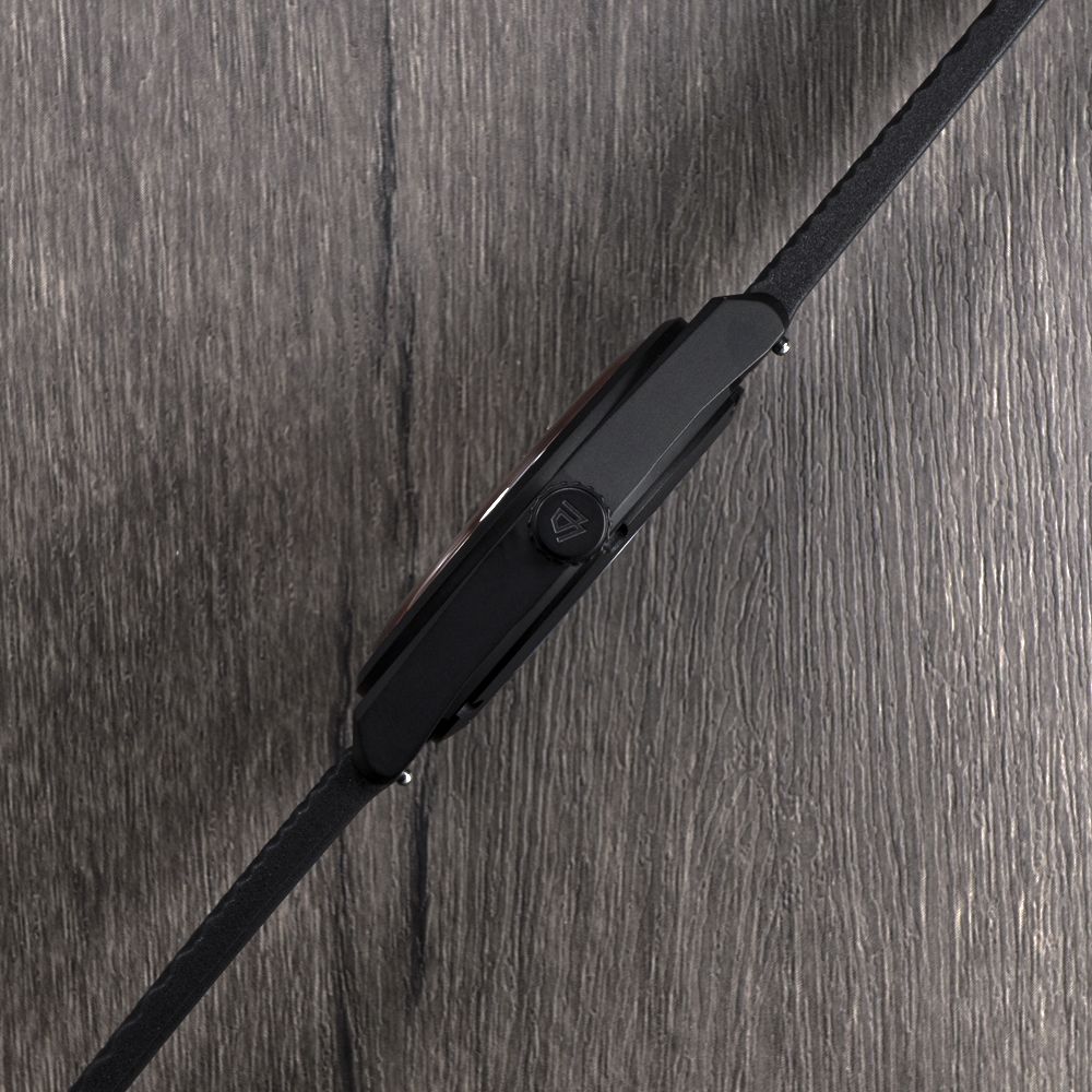 A close up of a black watch on a wooden table.