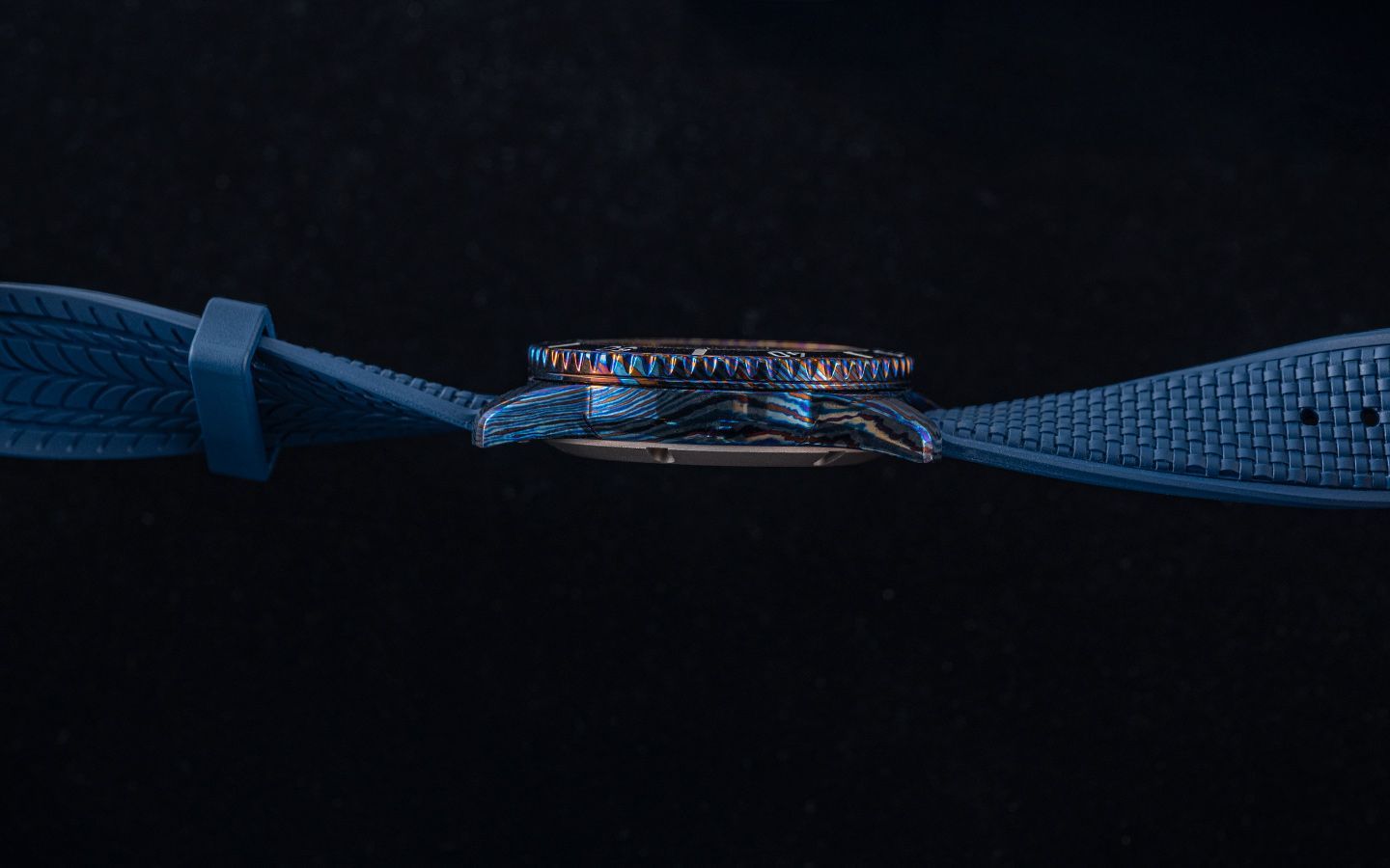 Side view of a watch with a textured blue strap against a black background.