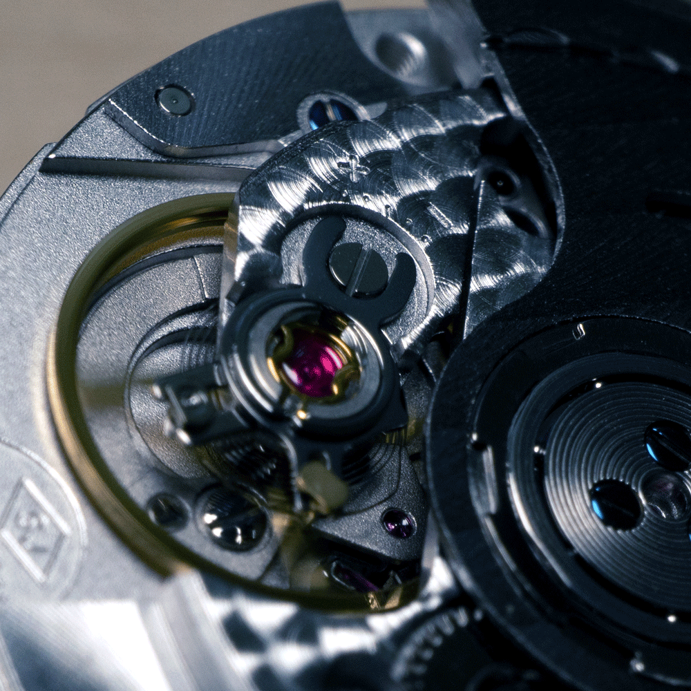 A close up of the inside of a watch with the letter t on it